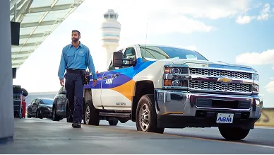 ABM employee walking outside in front of a truck with a colorful ABM decal